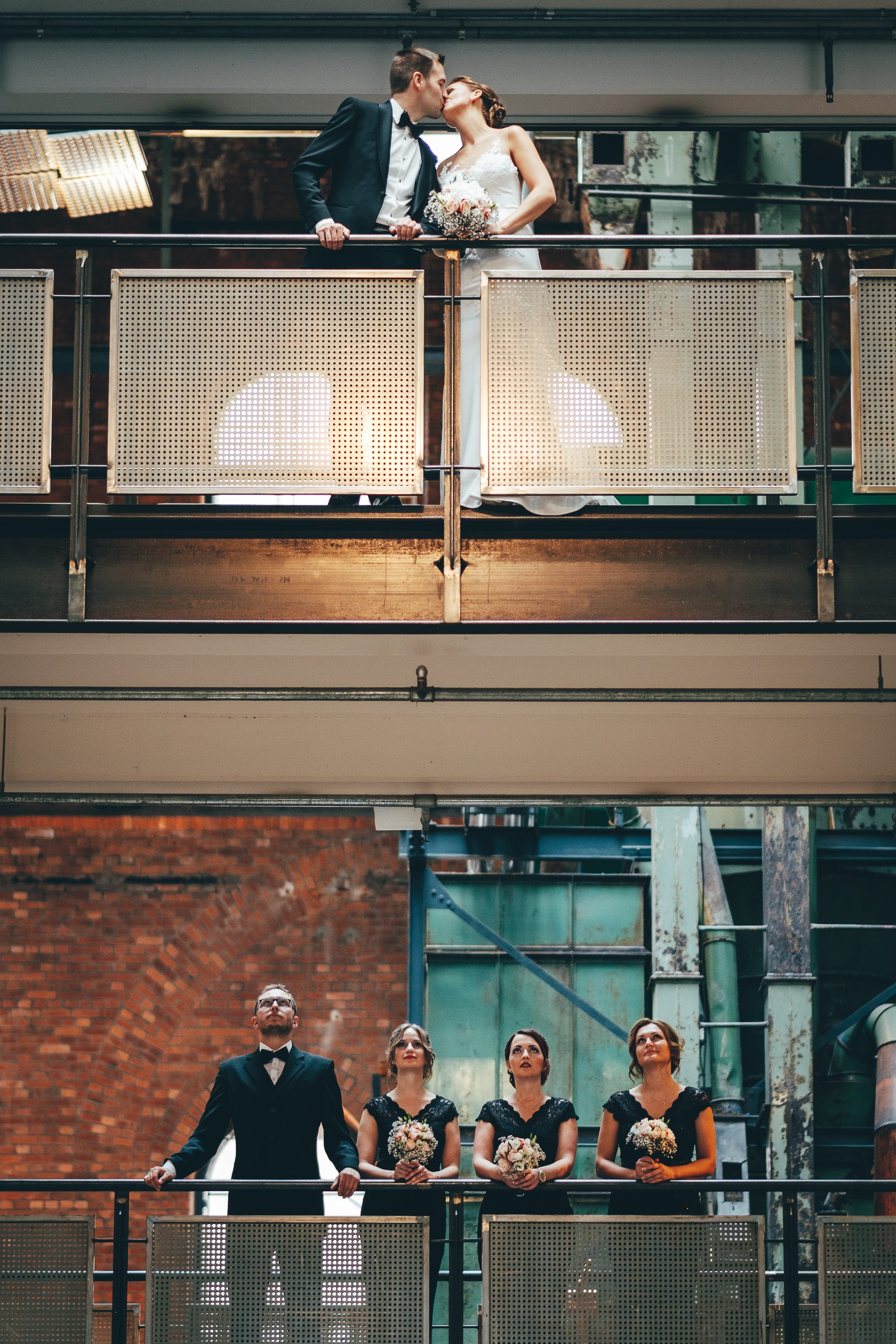 Brautpaar küsst sich auf Balkon mit Hochzeitsgesellschaft – Hochzeitsfotograf Hamburg Caro & Marc