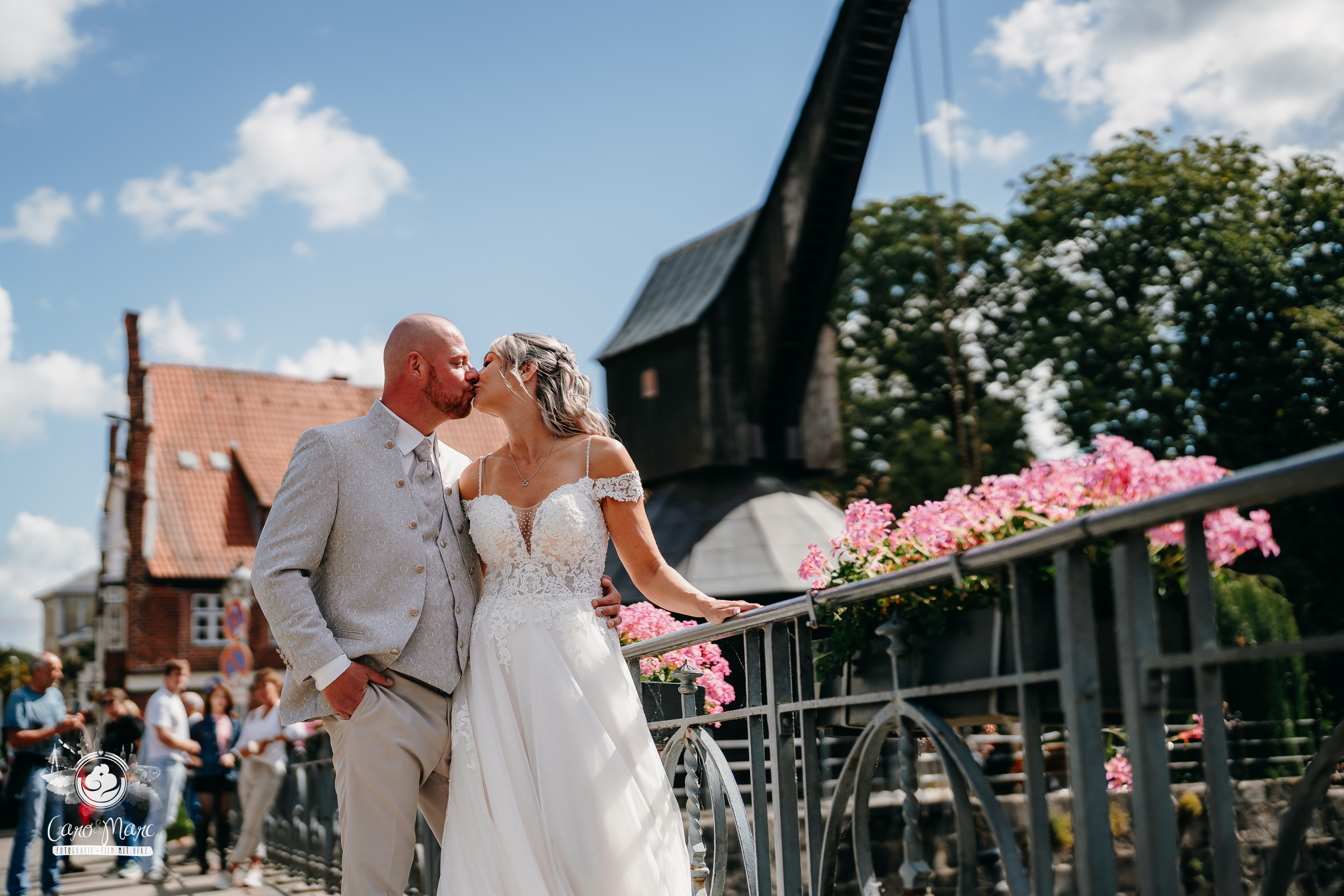 Brautpaar küsst sich auf Brücke vor Windmühle in Lüneburg – Hochzeitsfotograf Caro & Marc